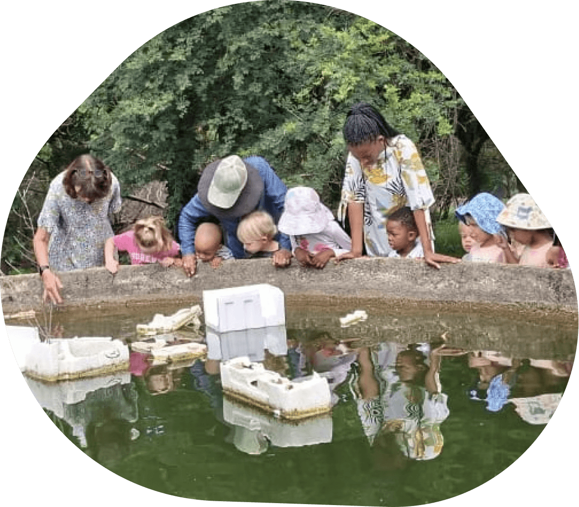 Children and teachers looking at floating boats on the pond at Kyalami Ridge