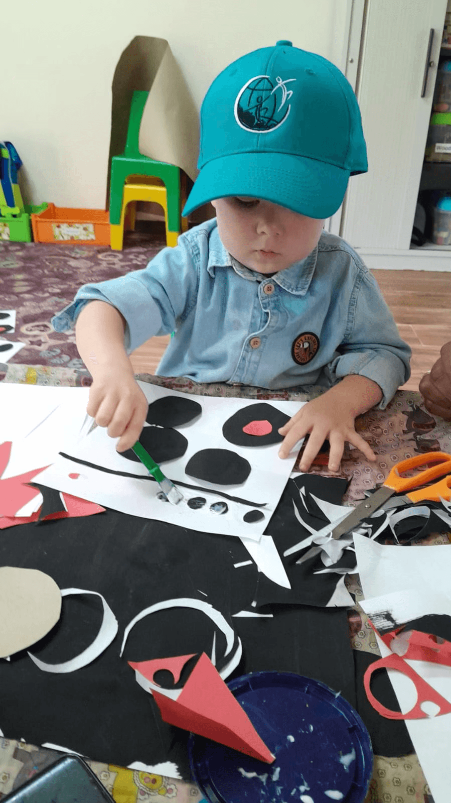 Child in a Kyalami Ridge cap making a paper collage