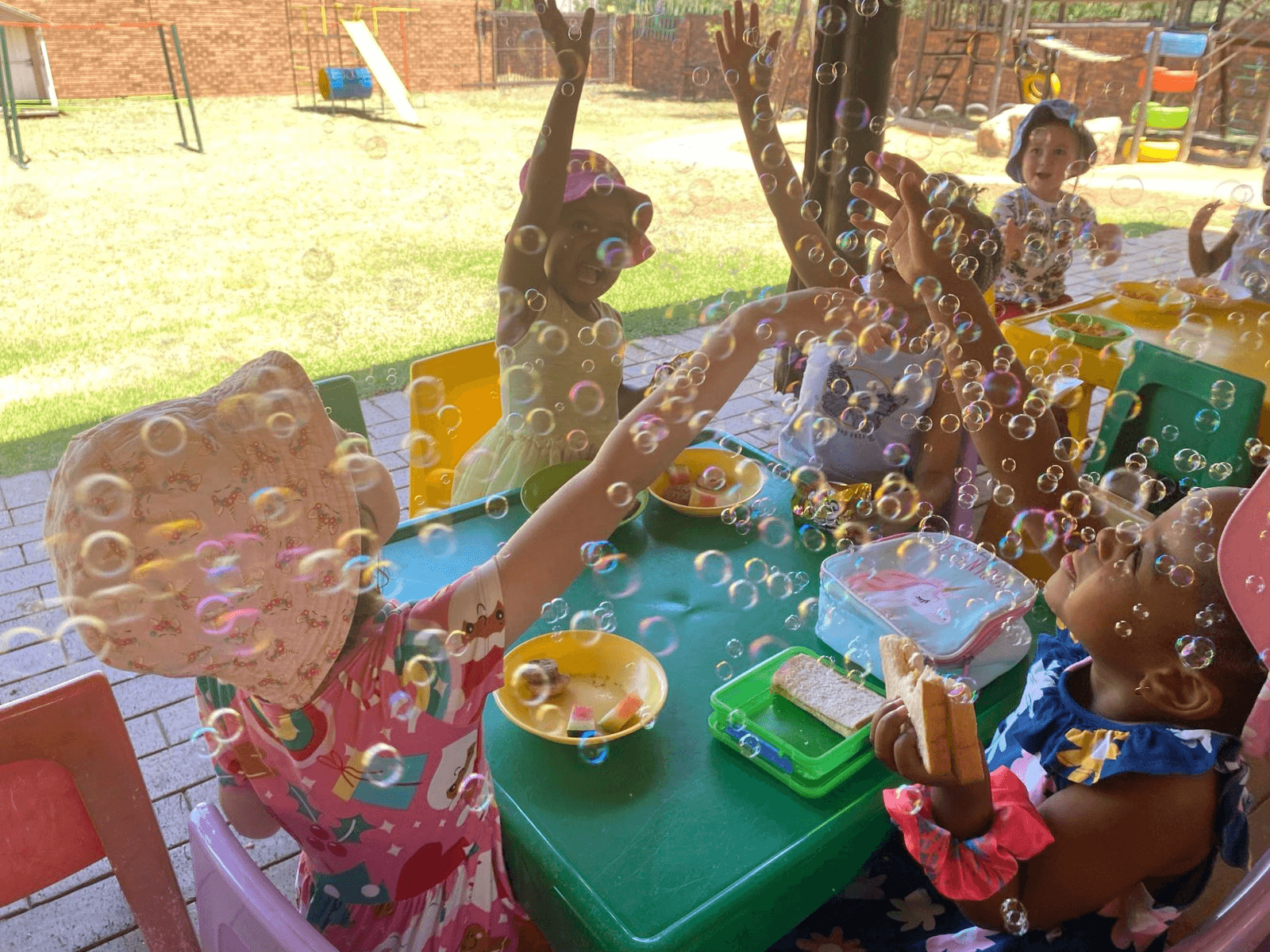 Children catching soap bubbles at their snack table outdoors