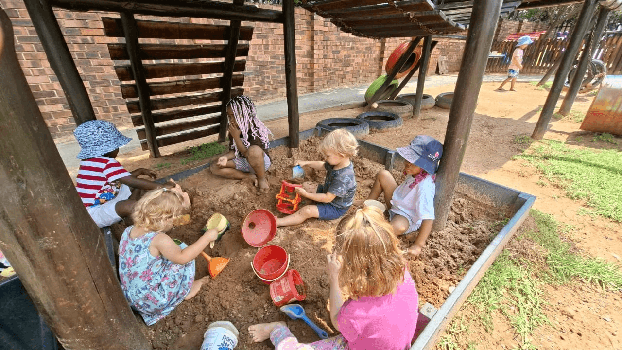 Children playing with buckets and spades in the sandpit at Kyalami Ridge